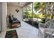 Screened porch with wicker furniture, tile flooring, and views of the landscaped yard at 3745 Almeria Ave # 7S, Sarasota, FL 34239