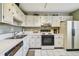 Cozy kitchen featuring white cabinets, tile floors and a stainless steel sink and vintage style refrigerator at 3820 Ironwood Ln # 104-I, Bradenton, FL 34209