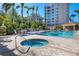 Beautiful pool and hot tub are surrounded by patio and palm trees with building in the background at 401 N Point Rd # 504, Osprey, FL 34229
