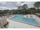 Large community pool with brick trim, lounge chairs, umbrellas, and mature trees at 401 N Point Rd # 504, Osprey, FL 34229