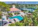 Overhead view of a pristine community pool with lounge chairs, tennis courts and lush landscaping at 401 N Point Rd # 504, Osprey, FL 34229