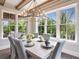 Light-filled dining room with seating for six, designer chandelier, and views of the lush landscape at 421 Alamanda Rd, Anna Maria, FL 34216