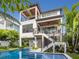 Stunning exterior view of a modern multi-story home with a beautiful pool and tropical landscaping at 421 Alamanda Rd, Anna Maria, FL 34216