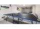 Garage game room features a ping pong table, television, putting green, speckled flooring and overhead door at 421 Alamanda Rd, Anna Maria, FL 34216