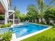 Beautiful backyard pool with an adjacent staircase leading to a balcony, surrounded by tropical landscaping at 421 Alamanda Rd, Anna Maria, FL 34216