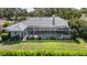 Rear exterior view of home featuring a screened pool, patio, and green lawn at 4374 Indian Point Trl, Sarasota, FL 34238