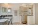 Bathroom featuring a glass enclosed shower and double sinks with stone floors and counters at 5044 Creekside Trl, Sarasota, FL 34243