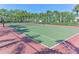 Well-maintained tennis court surrounded by green space and mature trees at 5044 Creekside Trl, Sarasota, FL 34243