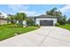Beautiful one-story home with a wide driveway, manicured lawn, and tropical landscaping at 5285 Far Oak Cir, Sarasota, FL 34238