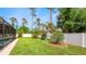 This backyard features lush green grass, landscaping, and a white vinyl fence for privacy at 5307 Kenvil Dr, North Port, FL 34288