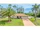 Charming single-story home with a well-maintained lawn, palm trees, and a two-car garage at 5307 Kenvil Dr, North Port, FL 34288