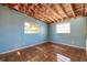 Bedroom features blue walls, natural light from two windows, and water-stained floors, ready for remodel at 5705 23Rd W St, Bradenton, FL 34207