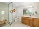 Bright bathroom featuring a glass shower enclosure, wooden accents and a large vanity with granite countertop at 610 Riviera Dunes Way # 503, Palmetto, FL 34221