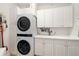 Well-organized laundry room with white cabinetry, countertop space, and modern stacked washer and dryer at 610 Riviera Dunes Way # 503, Palmetto, FL 34221