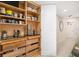 Open pantry with wooden shelves and drawers, showcasing ample storage space and a glimpse into the hallway at 610 Riviera Dunes Way # 503, Palmetto, FL 34221