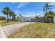 Well-maintained single-story home featuring lush palm trees, a wooden fence, and a concrete driveway at 6203 11Th W Ave, Bradenton, FL 34209