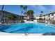 Sparkling community pool surrounded by a white fence, palm trees, and well-maintained buildings at 6300 Flotilla Dr # 108, Holmes Beach, FL 34217
