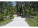 Gated gravel driveway leading to a secluded property surrounded by lush trees and landscaping at 7251 Fish Farm Rd, Palmetto, FL 34221
