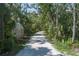 Gravel driveway surrounded by a canopy of trees and lush tropical landscaping at 7251 Fish Farm Rd, Palmetto, FL 34221