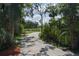 Gravel driveway through a lush, wooded landscape, leading to a distant field at 7251 Fish Farm Rd, Palmetto, FL 34221
