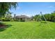 Expansive backyard featuring lush lawn, mature trees, and a swing set with a view of the home's rear facade at 7321 Hemlock Ln, Sarasota, FL 34241