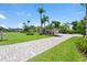 Long, elegant brick driveway leading to a well-maintained home with mature landscaping, palm trees, and a three-car garage at 7321 Hemlock Ln, Sarasota, FL 34241