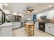 Well-lit kitchen featuring white cabinetry, black appliances, and a kitchen island with shelving at 7321 Hemlock Ln, Sarasota, FL 34241