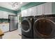 A modern laundry room with front-load washer and dryer, stainless steel fridge, and modern lighting at 7321 Hemlock Ln, Sarasota, FL 34241