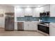 Modern kitchen with stainless steel appliances, white cabinetry, and beautiful blue tile backsplash at 7404 13Th Avenue W Dr, Bradenton, FL 34209