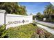 Sandhill Lake community entrance with a stone sign surrounded by lush tropical plants and flowers at 8020 Clearwater Ct, Sarasota, FL 34241