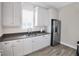 Bright kitchenette features white cabinets, stainless steel refrigerator, gray countertops, and hardwood floors at 8020 Clearwater Ct, Sarasota, FL 34241