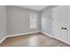 Bedroom with wood-look tile floor and light grey walls, window and white door at 8962 Baroque Ter, Sarasota, FL 34240