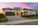 Charming house with a three-car garage, paver driveway, stone accents, and manicured landscaping at sunset at 8962 Baroque Ter, Sarasota, FL 34240