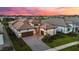 Beautifully landscaped home with a tile roof, three-car garage, and a paver driveway under a colorful sunset sky at 8962 Baroque Ter, Sarasota, FL 34240