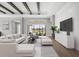 Living room with exposed beam ceiling, contemporary furniture, and large windows overlooking the landscaped yard at 8962 Baroque Ter, Sarasota, FL 34240