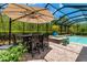 Covered outdoor dining area features a large table, chairs, umbrella, and access to the pool and spa at 932 Mangrove Edge Ct, Bradenton, FL 34208