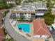 Aerial view of community pool with lounge chairs, umbrellas, and shuffleboard in quiet community at 110 Vista Hermosa Cir # 302B, Sarasota, FL 34242