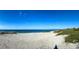 Panoramic view of a sandy beach meeting the ocean under a bright, clear sky at 110 Vista Hermosa Cir # 302B, Sarasota, FL 34242