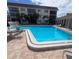 Community pool surrounded by a brick patio, lounge chairs, and palm trees at 110 Vista Hermosa Cir # 302B, Sarasota, FL 34242