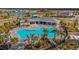 Aerial view of a community pool area featuring a uniquely shaped pool, lounge chairs, and palm trees at 12047 Lansing Gln, Parrish, FL 34219