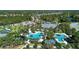 A high aerial shot presents a community center with pools, water slide and playground surrounded by lush greenery and Gathering homes at 12229 Stuart Dr, Venice, FL 34293