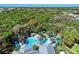 Overhead shot showcasing a uniquely shaped pool with palm trees, a hot tub, and cabanas surrounded by vibrant trees at 12229 Stuart Dr, Venice, FL 34293