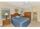 Bedroom with a ceiling fan, two windows, and wooden furniture and door to bath at 12229 Stuart Dr, Venice, FL 34293