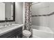Stylish bathroom with a granite vanity, tub/shower with patterned curtain, and elegant tile accents at 12856 Sorrento Way, Bradenton, FL 34211