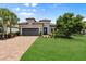 Beautifully landscaped home featuring a well-maintained lawn, brick driveway, and modern architectural details at 12856 Sorrento Way, Bradenton, FL 34211