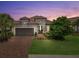 Charming single-story home featuring a tile roof, brick driveway, and a well-manicured front yard at twilight at 12856 Sorrento Way, Bradenton, FL 34211