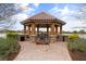 Scenic gazebo with brick path, stone accents, and seating overlooking a tranquil lake and lush landscaping at 12856 Sorrento Way, Bradenton, FL 34211