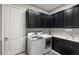 Modern laundry room featuring a washer, dryer, and dark cabinets at 12856 Sorrento Way, Bradenton, FL 34211
