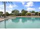 Relaxing community pool with cabanas, surrounded by lush landscaping and clear blue skies on a sunny day at 12856 Sorrento Way, Bradenton, FL 34211