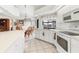 All-white kitchen with tile floors includes an island with bar seating and an adjacent dining area with wicker chairs at 1304 Alton Rd, Port Charlotte, FL 33952